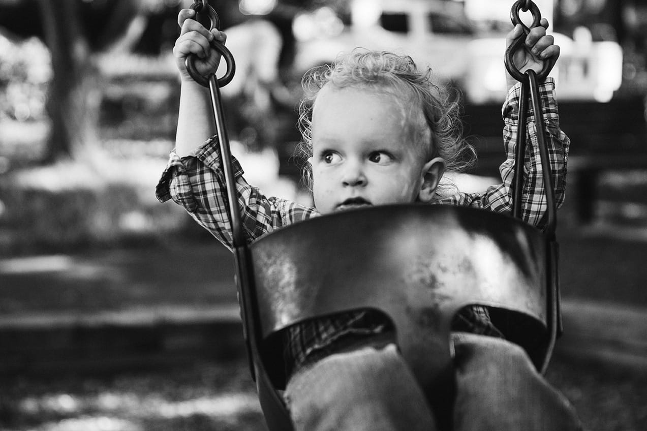 A lifestyle portrait of a toddler on the swings during an in home family session in Boston