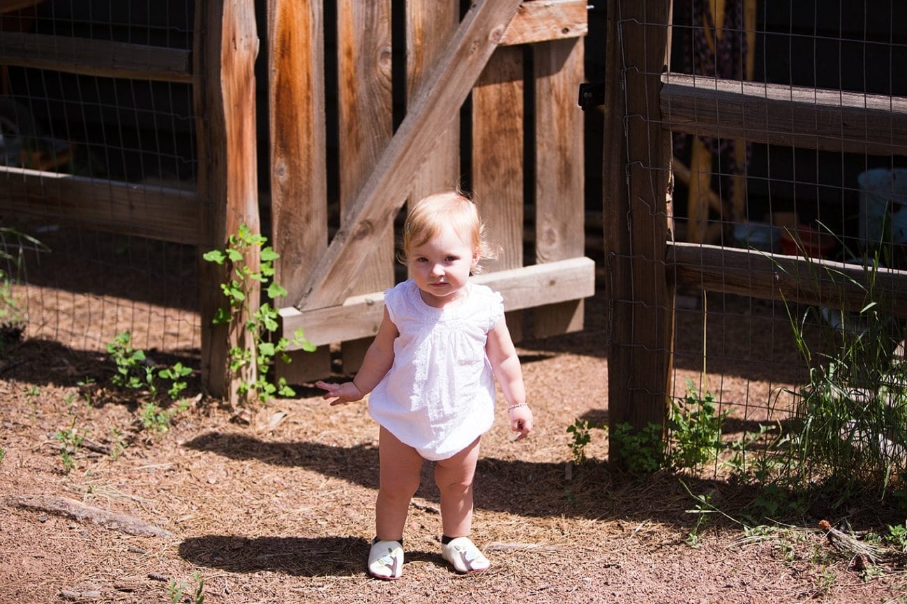 A documentary portrait of a toddler walking outside her family home during a evergreen family session in Colorado