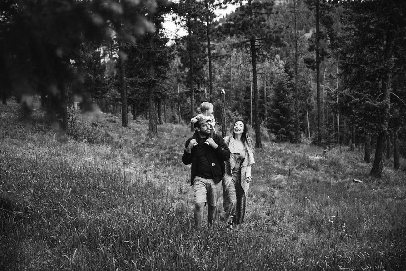 A documentary photograph of a family walking through their backyard during an evergreen family session at home in Colorado