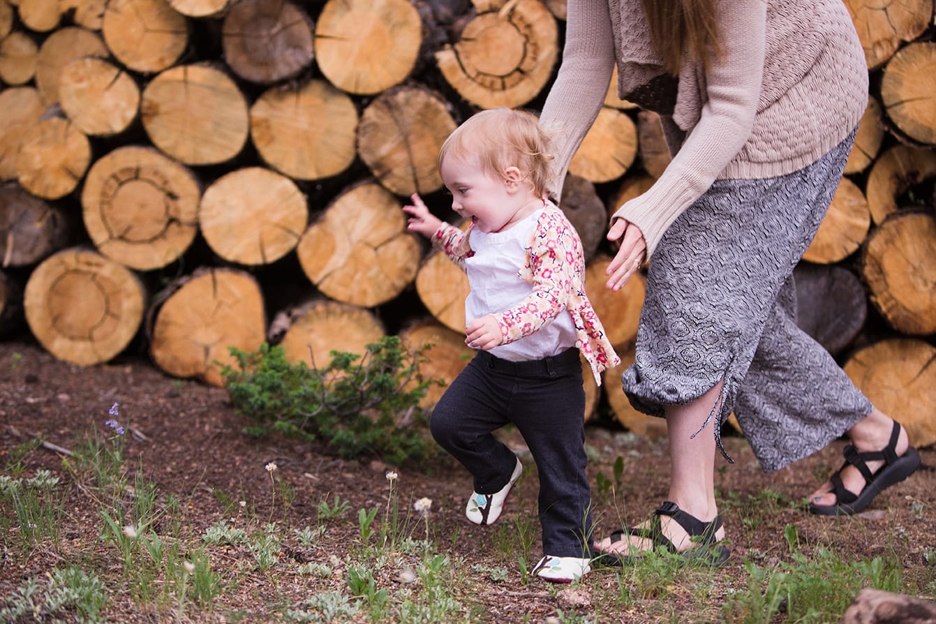 A documentary photograph of mom chasing her daughter during an evergreen family session at home in Colorado