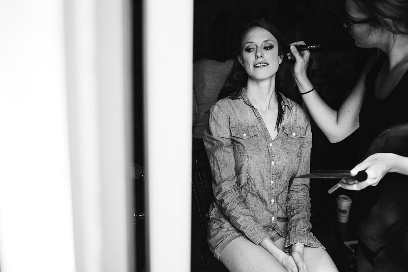 A documentary photograph of a bride getting her makeup done before her Kingsley Pines Camp Wedding in Maine