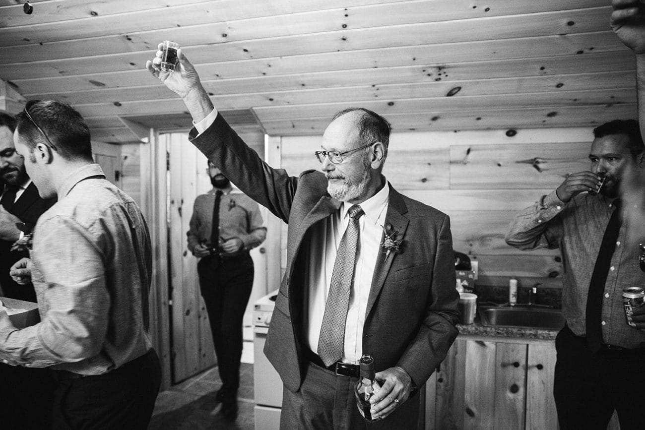 A documentary photograph of the father of the groom making a toast before a Kingsley Pines Camp Wedding in Maine