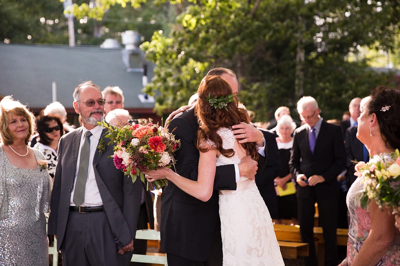 A documentary photograph of a bride hugging her father at the altar during a Kingsley Pines Camp Wedding in Maine