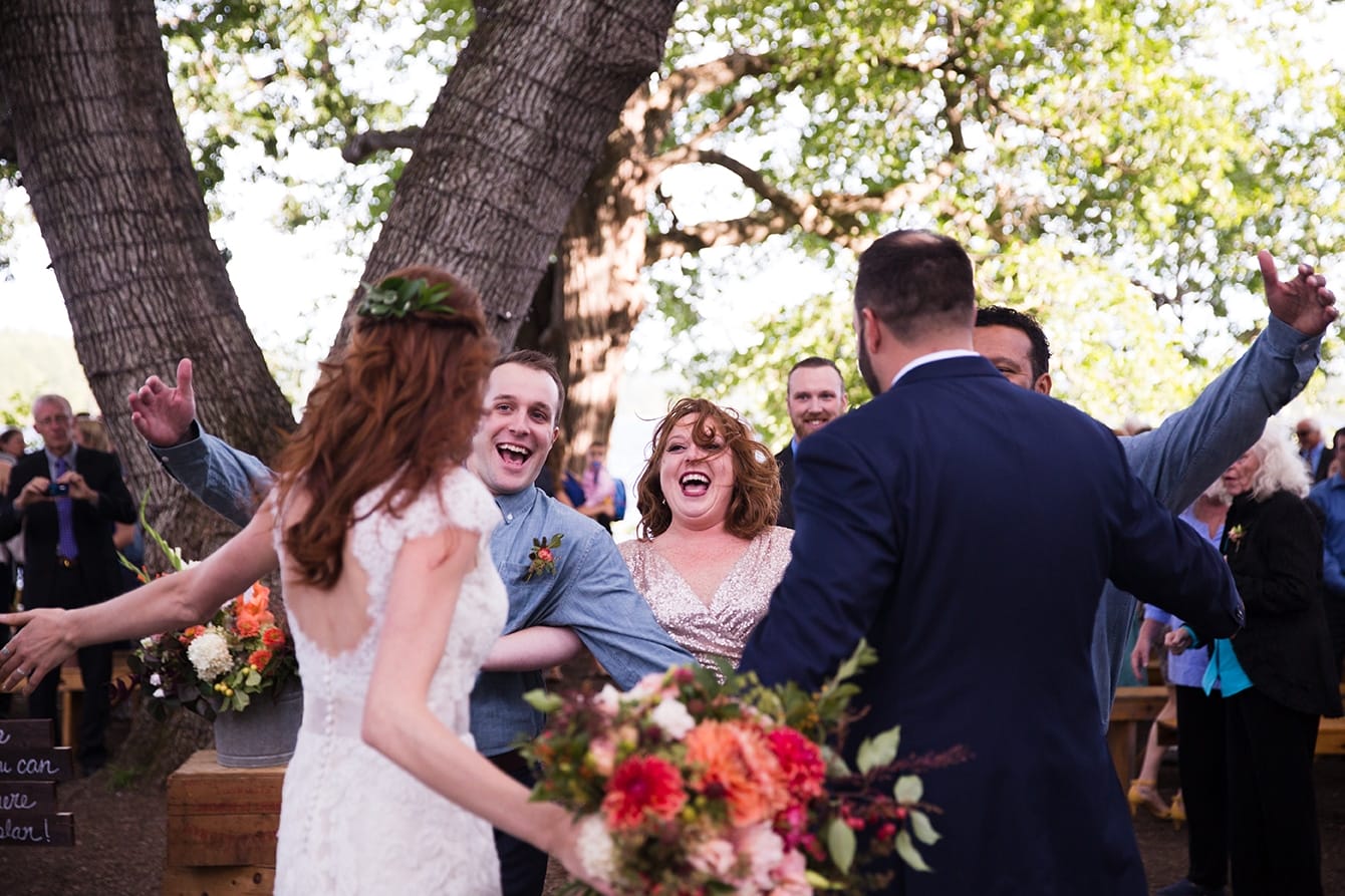A documentary photograph of a bride and groom hugging friends after their outdoor wedding ceremony at Kingsley Pines Camp in Maine