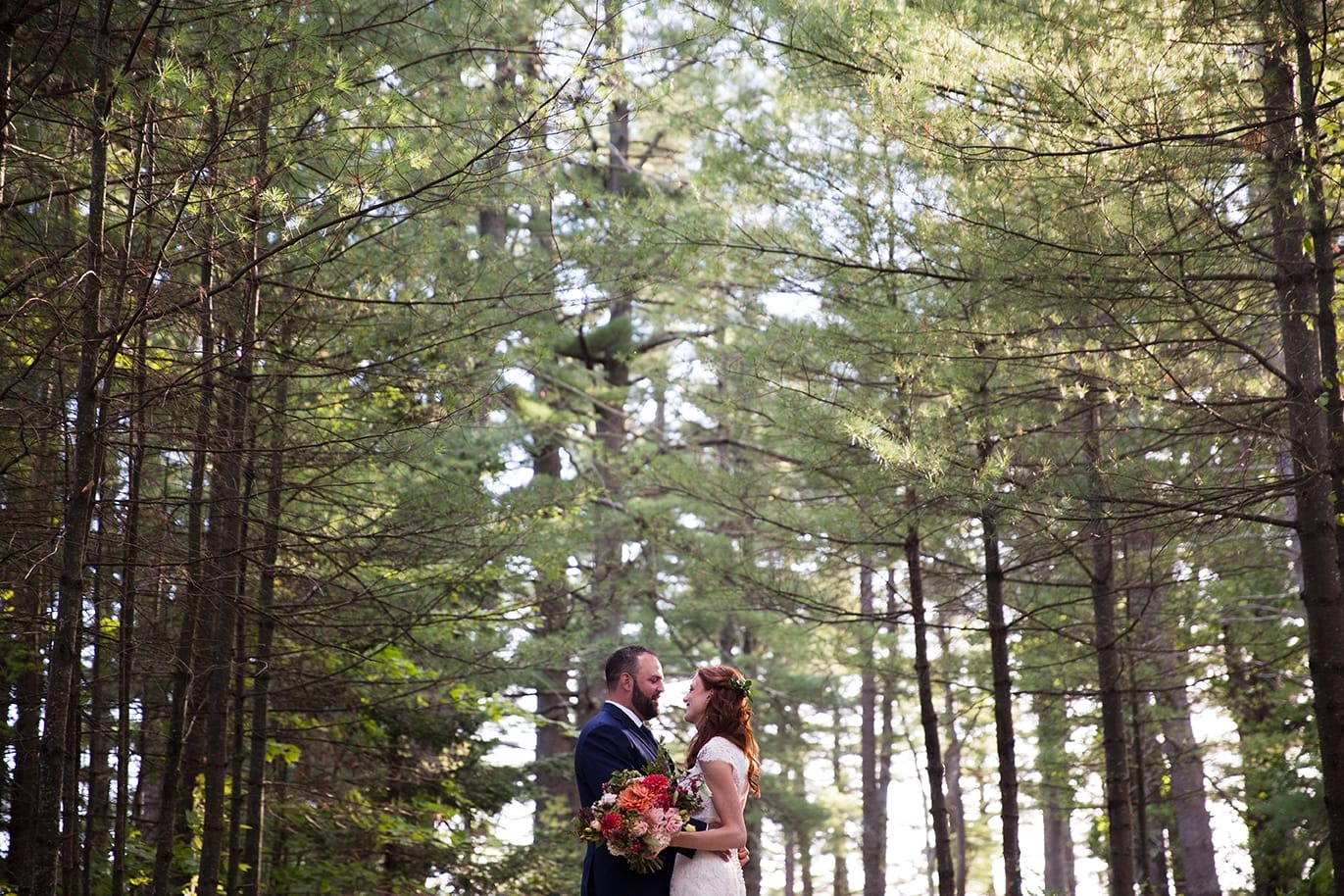 A natural portrait of a bride and groom in the woods during their Kingsley Pines Camp Wedding in Maine