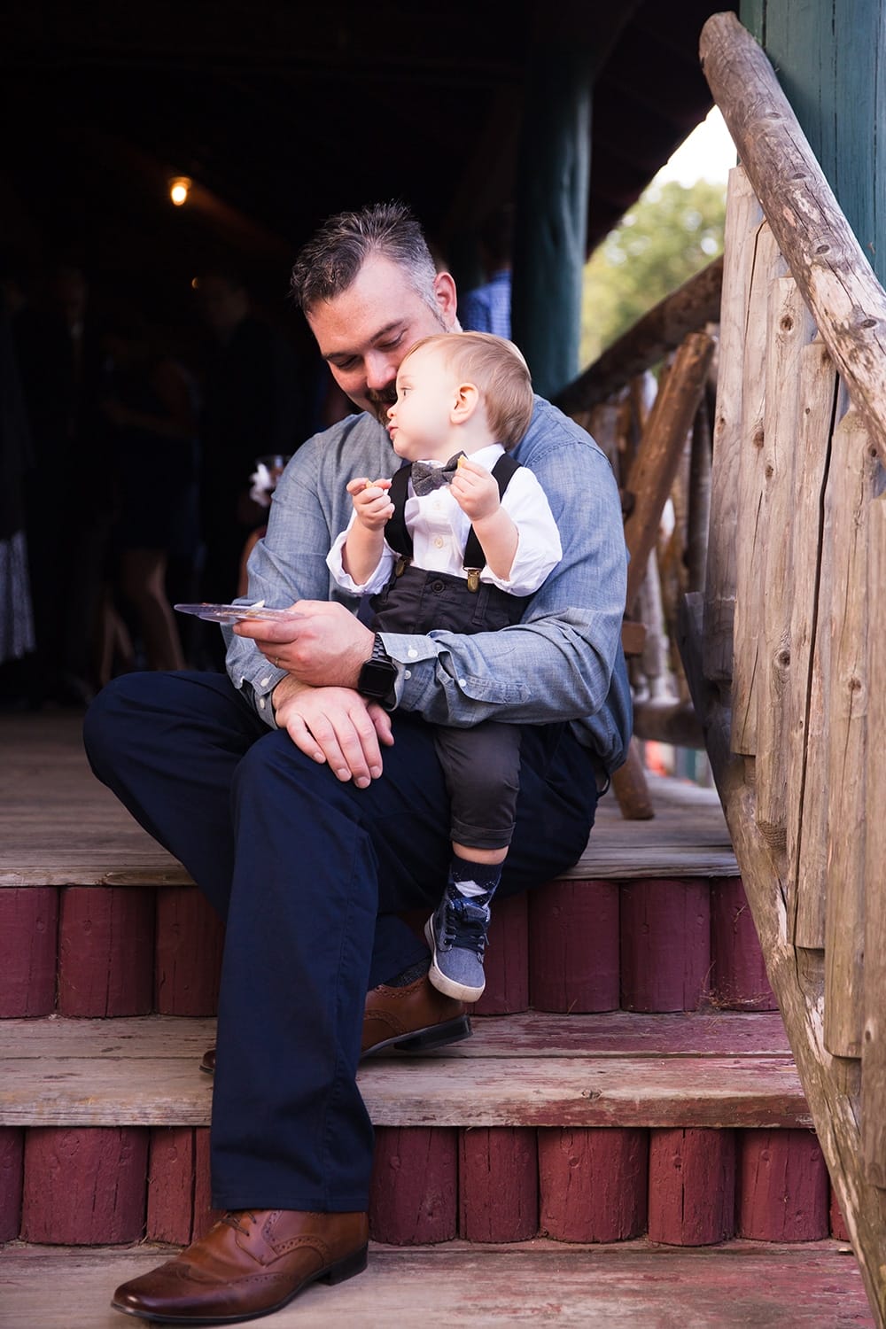 A documentary photograph of a father and son having some food during cocktail hour at a Kingsley Pines Camp Wedding in Maine