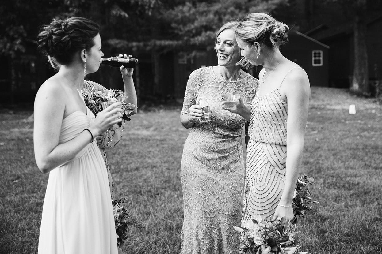 A documentary photograph of bridesmaids talking during a Kingsley Pines Camp wedding in Maine