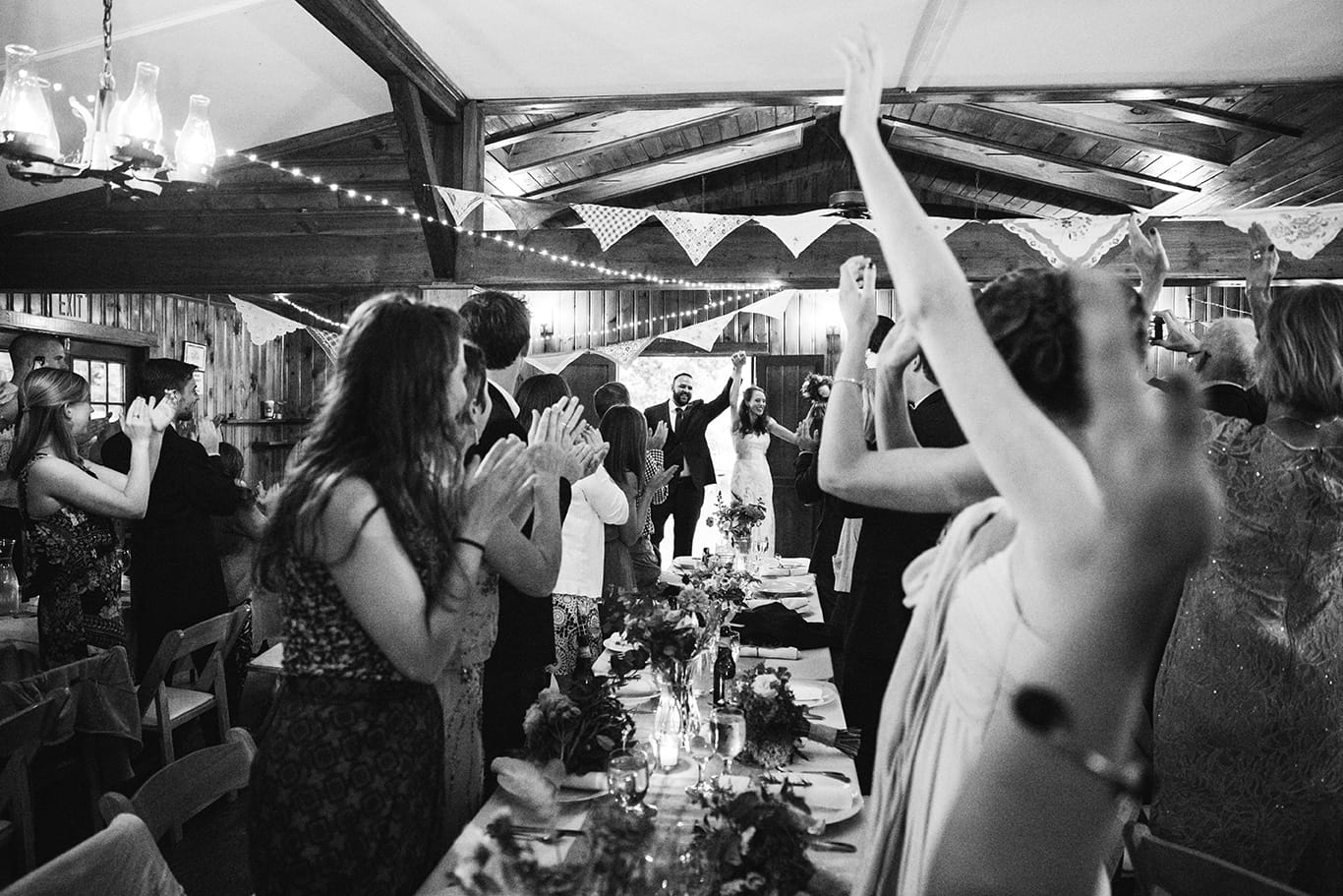 A documentary photograph of the bride and groom entering their reception at a Kingsley Pines Camp Wedding in Maine