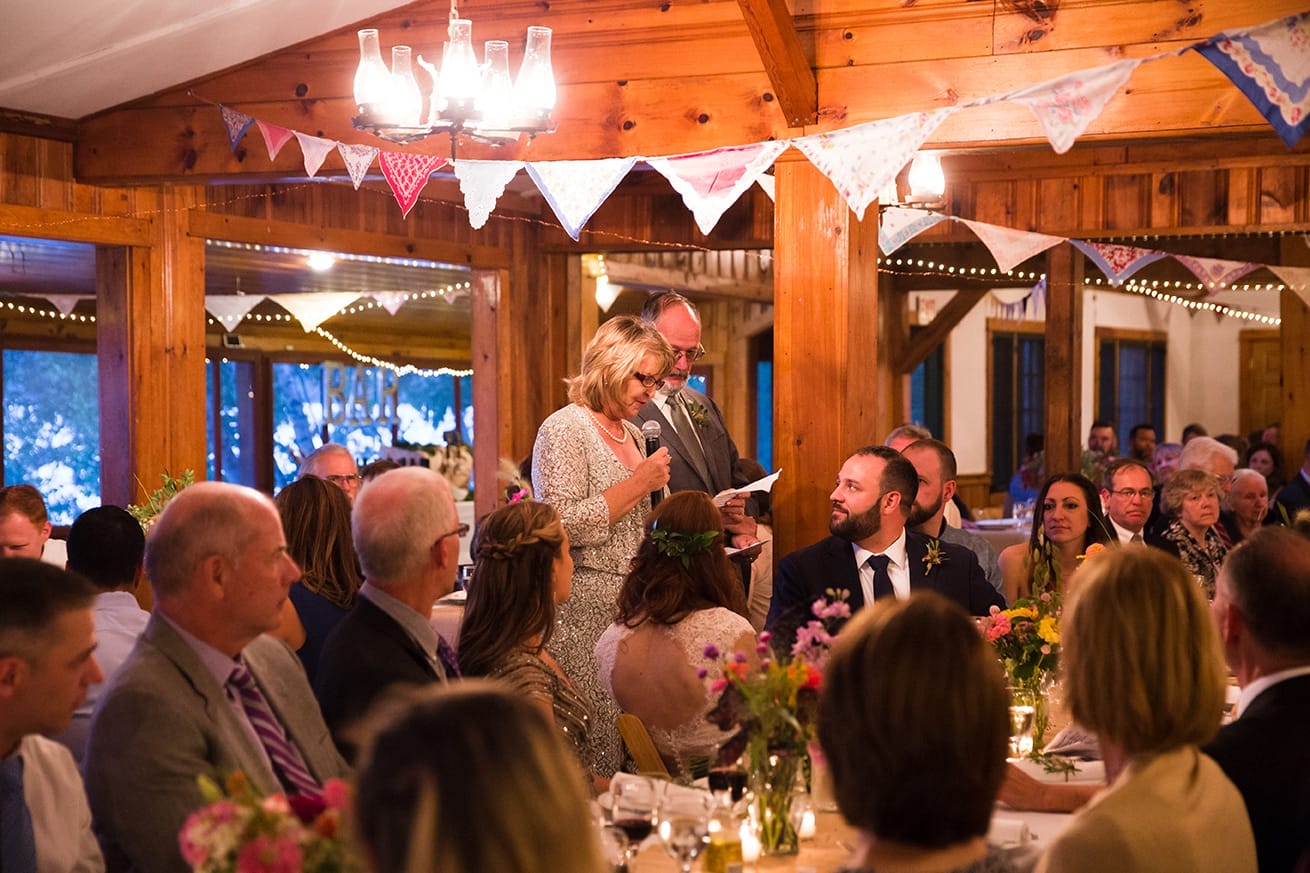 A documentary photograph of the parents giving a toast during a Kingsley Pines Camp Wedding in Maine