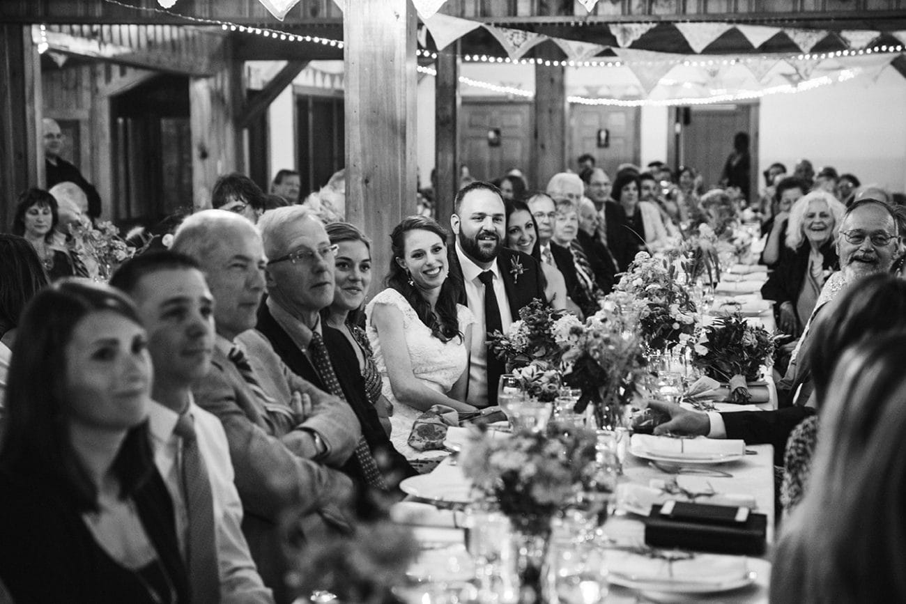 A documentary photograph of guest listening the best man speech at at Kingsley Pines Camp Wedding in Maine