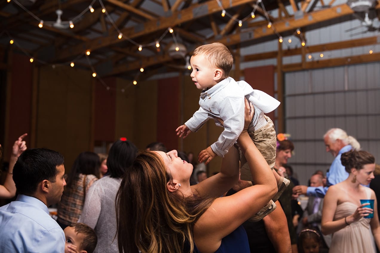 A documentary photograph of a mom dancing with her baby boy during a Kingsley Pines Camp Wedding in Maine