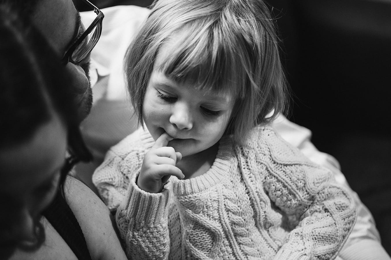 A toddler looks down at her new baby sister during an in home newborn session in the Jamaica Plain neighbourhood of Boston, Massachusetts