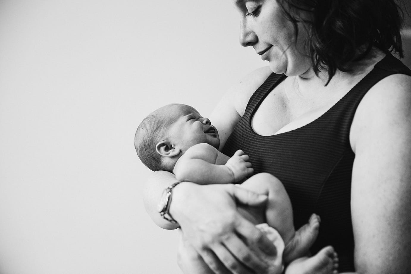 A mother cuddles and soothes her new baby girl during an in home newborn session in the Jamaica Plain neighbourhood of Boston, Massachusetts