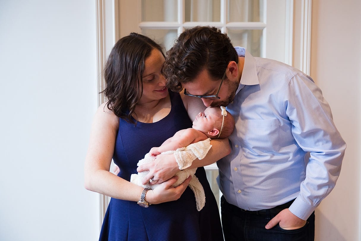 A relaxed portrait of a mother and father with new baby girl during an in home newborn session in the Jamaica Plain neighbourhood of Boston, Massachusetts
