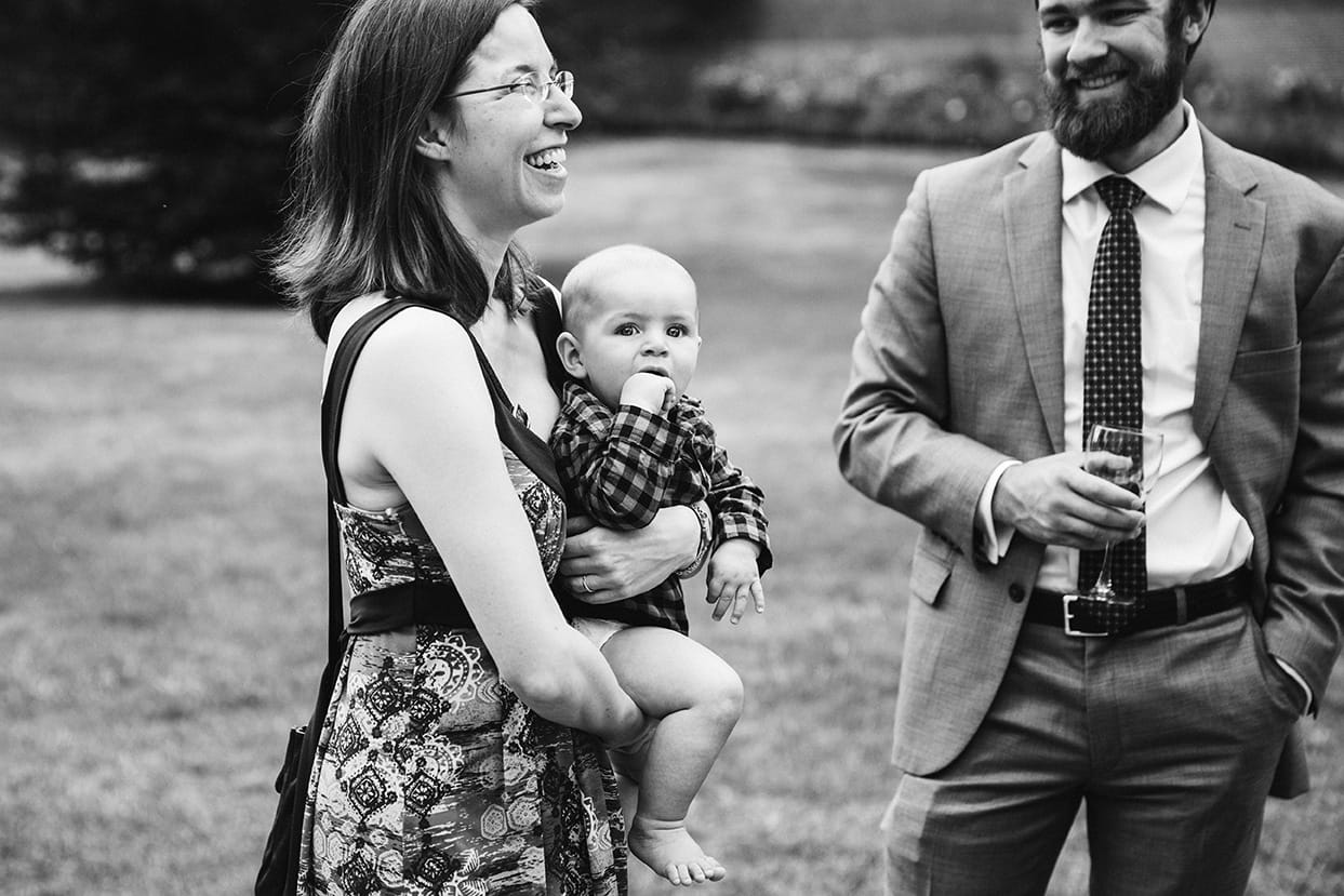 A documentary photograph of woman laughing while holding a baby during a Lyman Estate Wedding in Boston, Massachusetts
