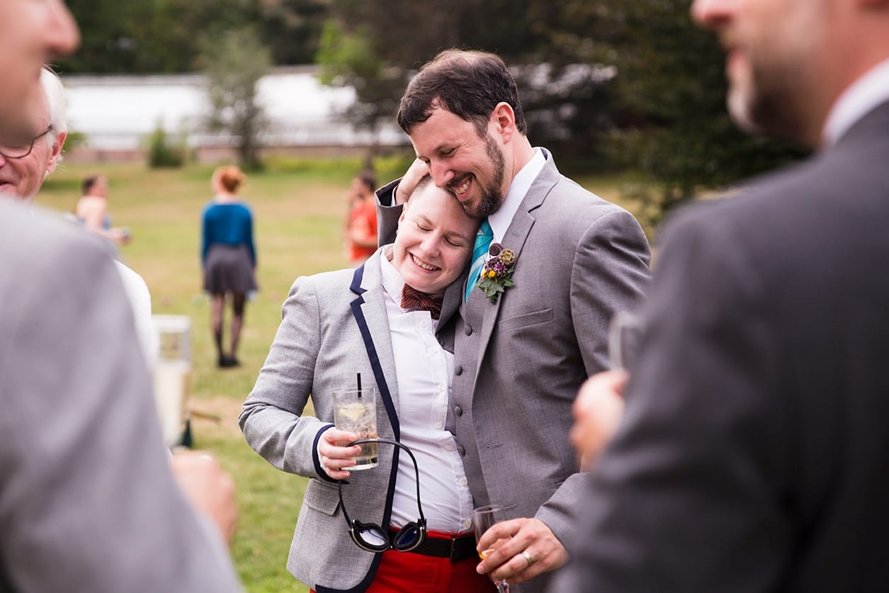 A documentary photograph of a Groom hugging his friend during the cocktail hour of a Lyman Estate Wedding in Boston, Massachusetts