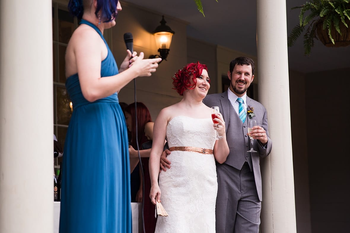 A documentary photograph of a bride and groom smiling during the maid of honour speech at a Lyman Estate Wedding in Boston, Massachusetts