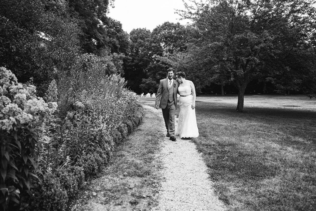 A documentary photograph of a bride and groom walking to the reception of their Lyman Estate Wedding in Boston, Massachusetts