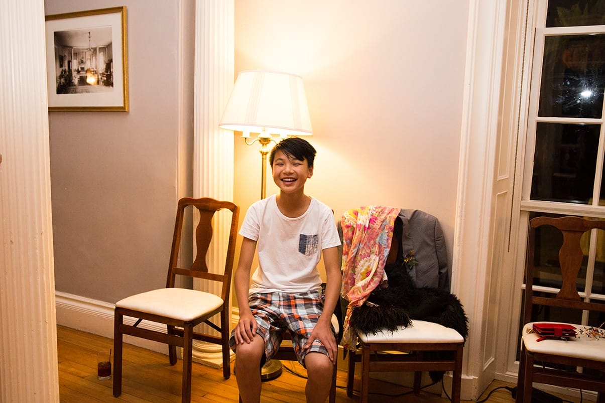 A documentary photograph of a boy laughing at the guests dancing during a Lyman Estate Wedding in Boston, Massachusetts