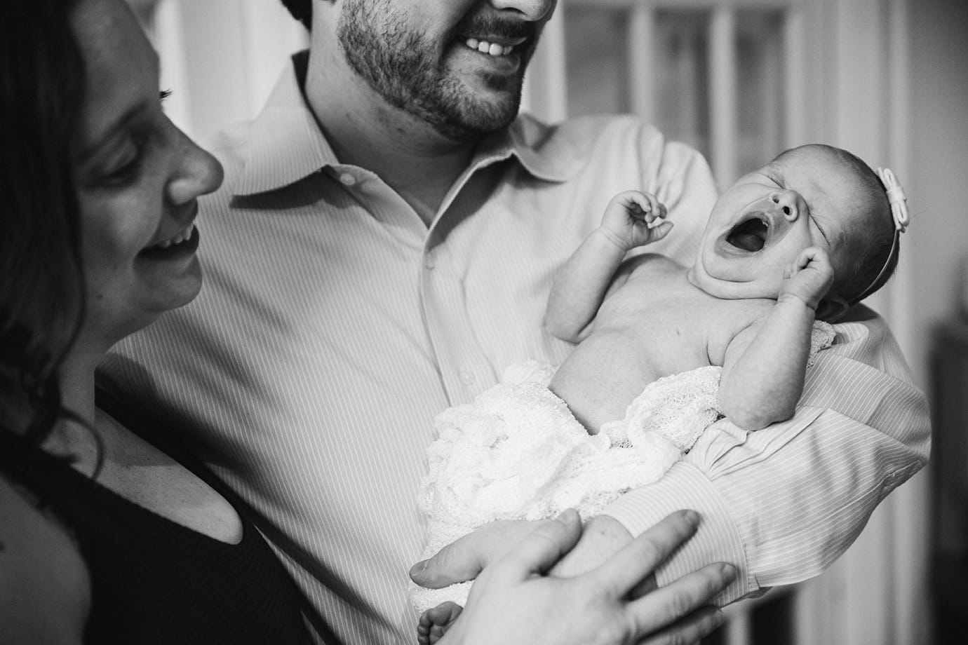 This documentary photograph of a newborn yawning in her father's arms is one of the best family photographs of 2016