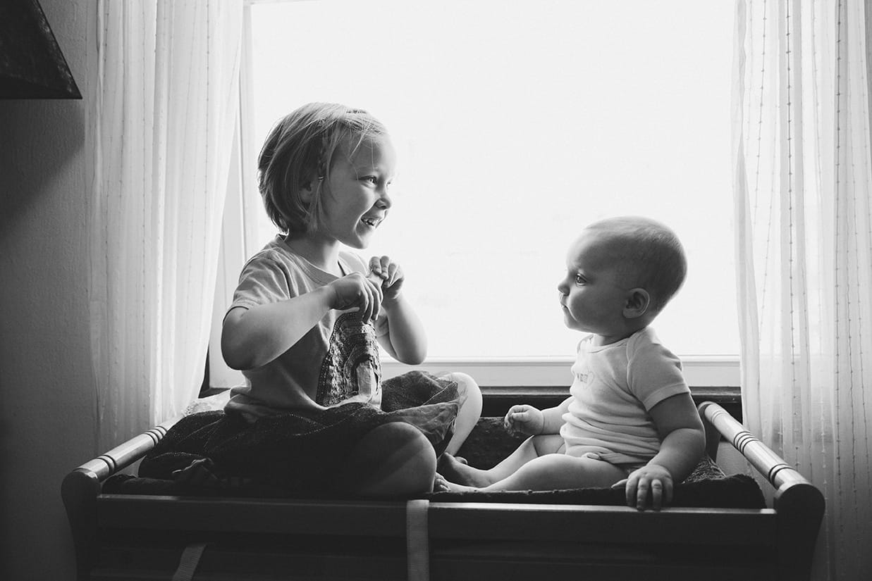 This documentary photograph of a two sisters sitting on the change table is one of the best family photographs of 2016