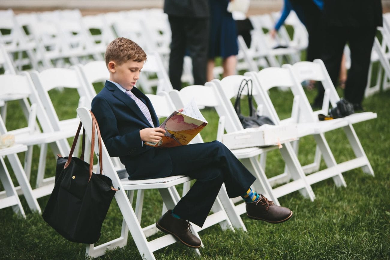 This documentary photograph of a boy reading comics during a wedding ceremony is one of the best wedding photographs of 2016