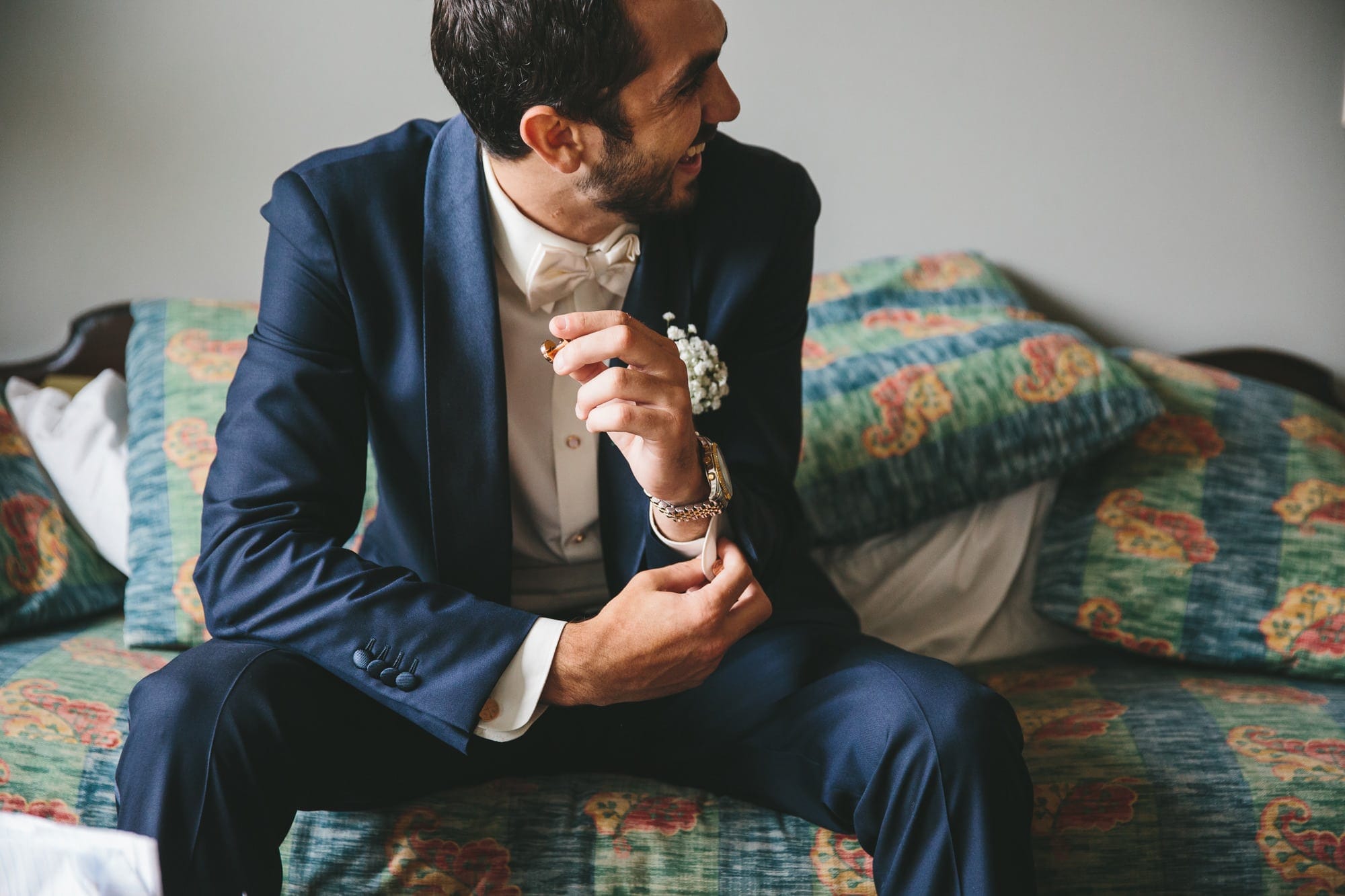 This documentary photograph of a groom laughing while putting on cuff links is one of the best wedding photographs of 2016 