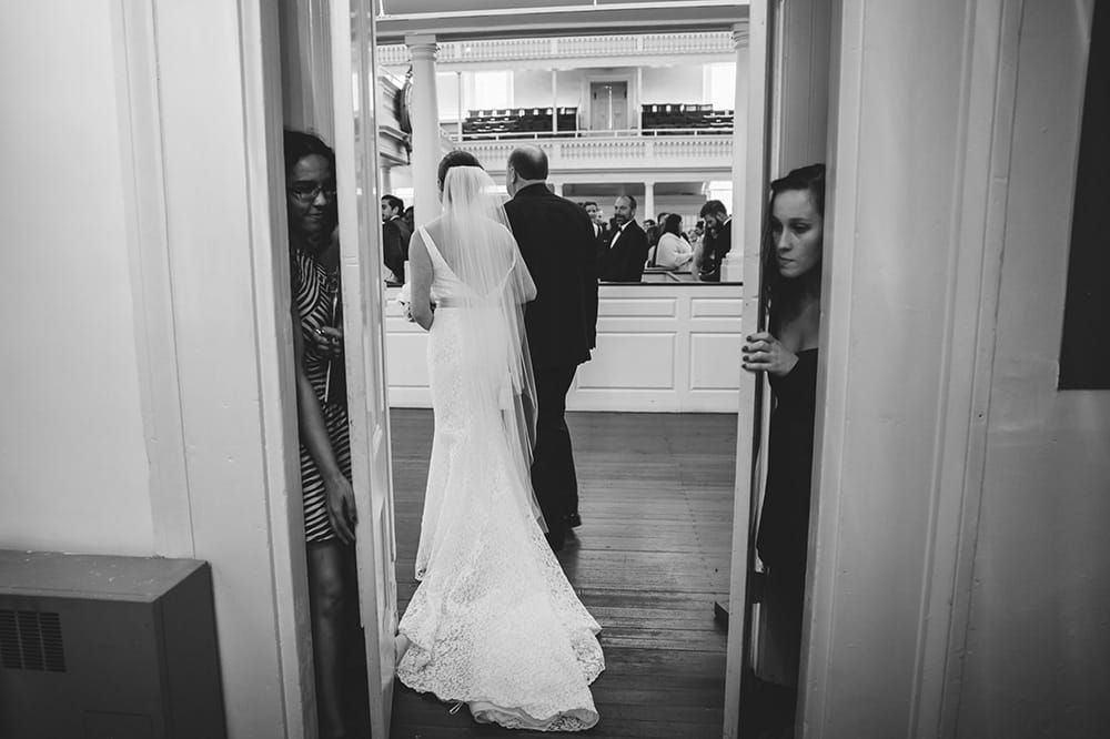 This documentary photograph of a bride walking up the aisle at her old south meeting house wedding is one of the best wedding photographs of 2016