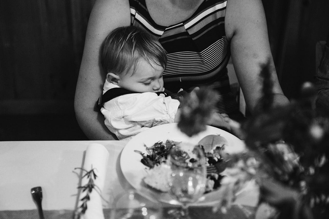 This documentary photograph of a baby sleeping in his mothers arms during a wedding reception is one of the best wedding photographs of 2016