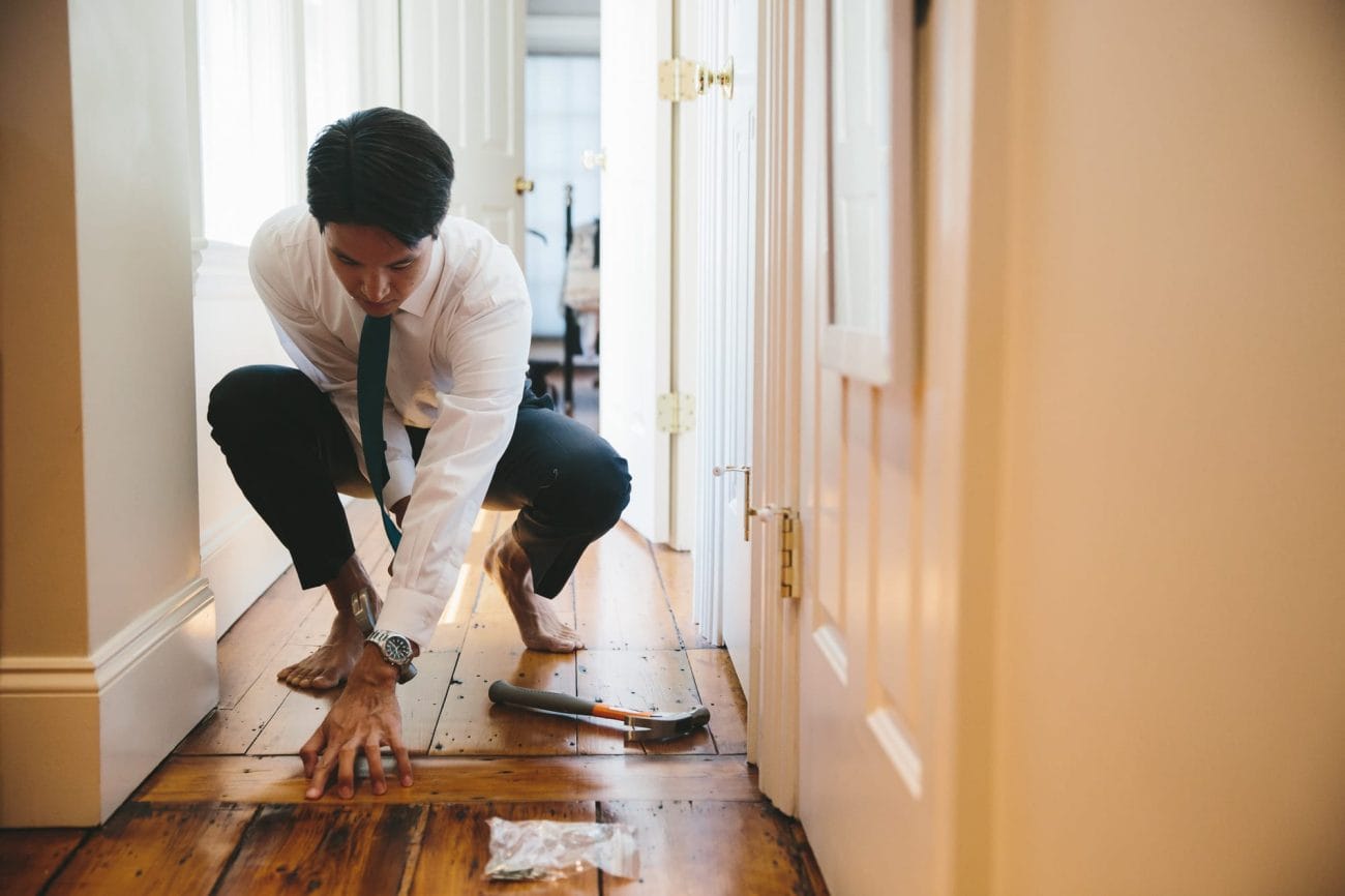 A documentary photograph of a groom fixing the groom's floor before his Artists for Humanity Wedding in Boston, Massachusetts
