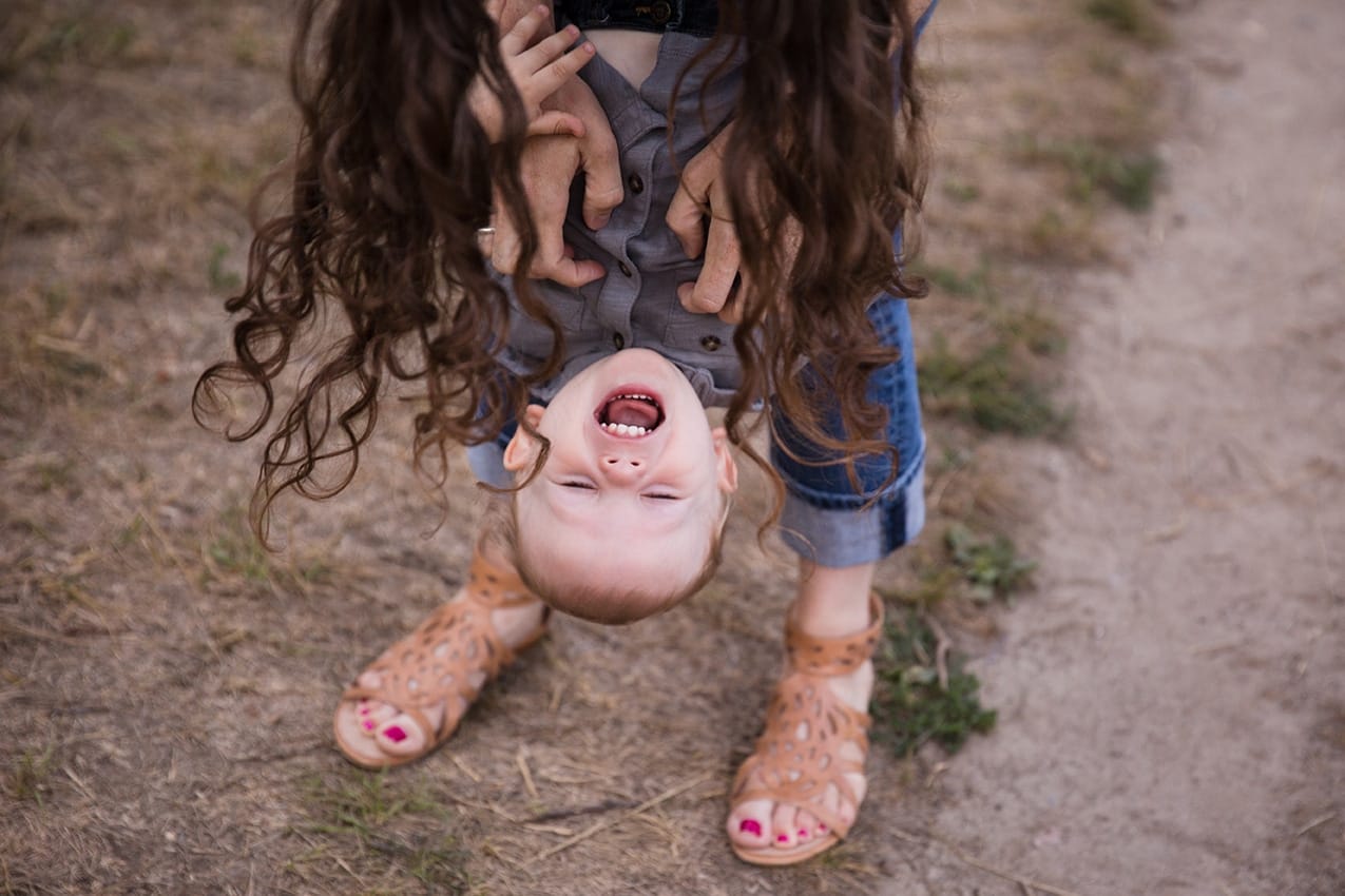 A documentary photograph of a mom tickling her son during their Arnold Arboretum Family Session in Boston, Massachusetts