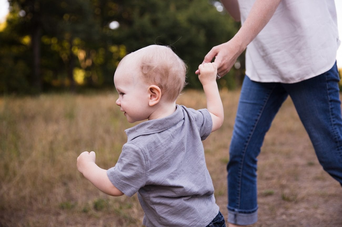 A documentary photograph of a mom running with her son during an Arnold Arboretum Family Session in Boston, Massachusetts