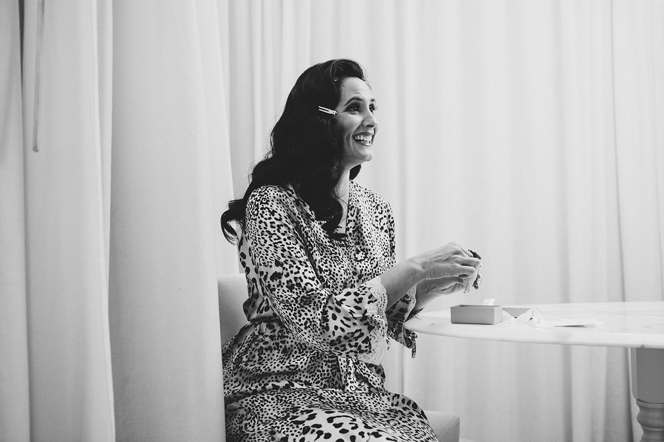 A documentary photograph of bride opening a gift from her groom on the morning of their old south meeting house and marliave wedding in Boston, Massachusetts