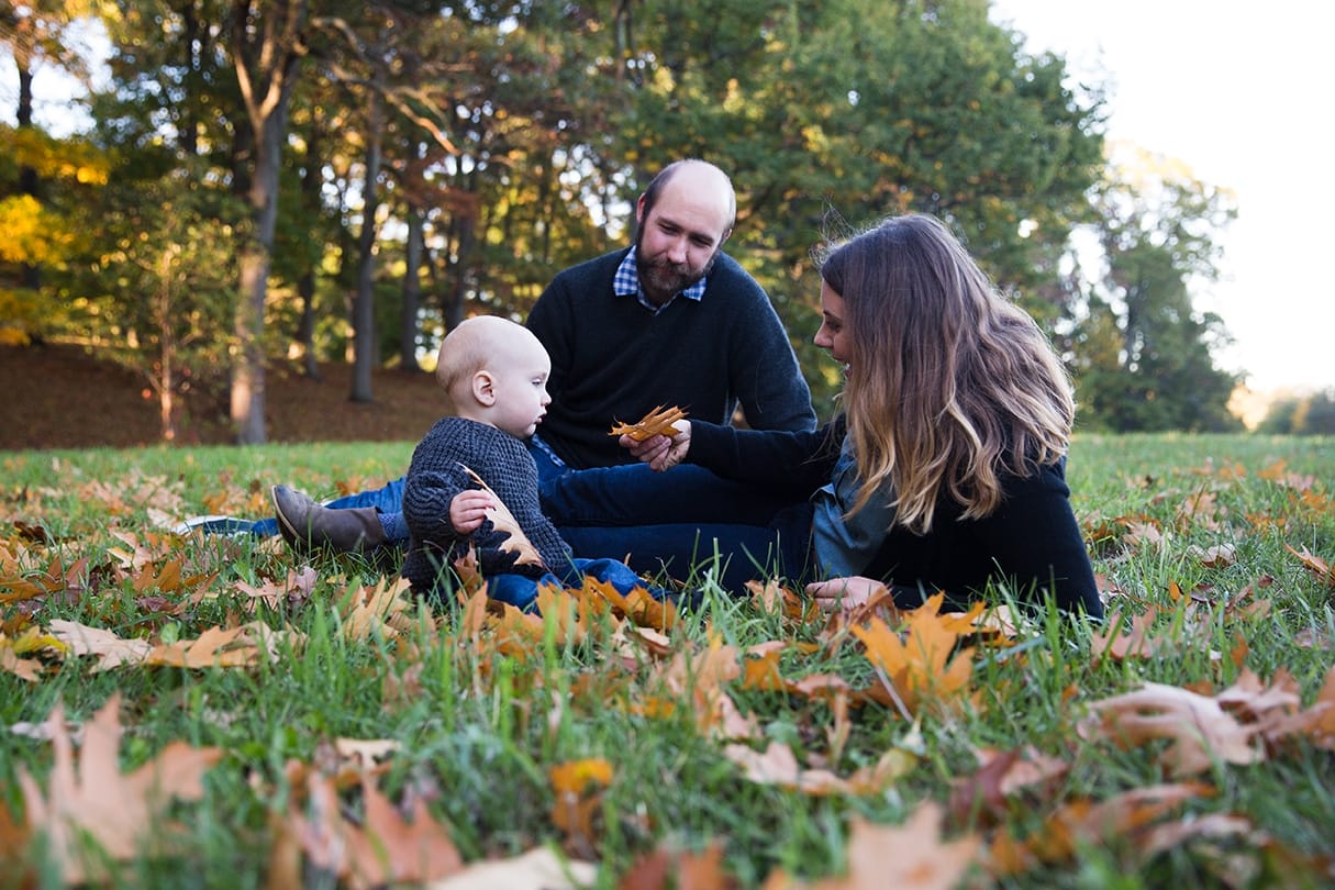A documentary photograph of a family playing in in the leaves during their lifestyle family photo session at the Arnold Arboretum