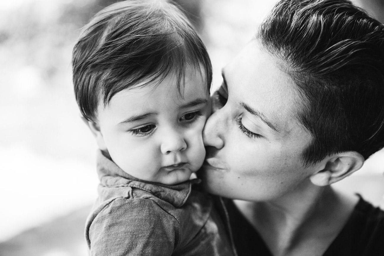 A lifestyle portrait of a mother kissing her son during a Jamaica Pond family session in Boston, Massachusetts