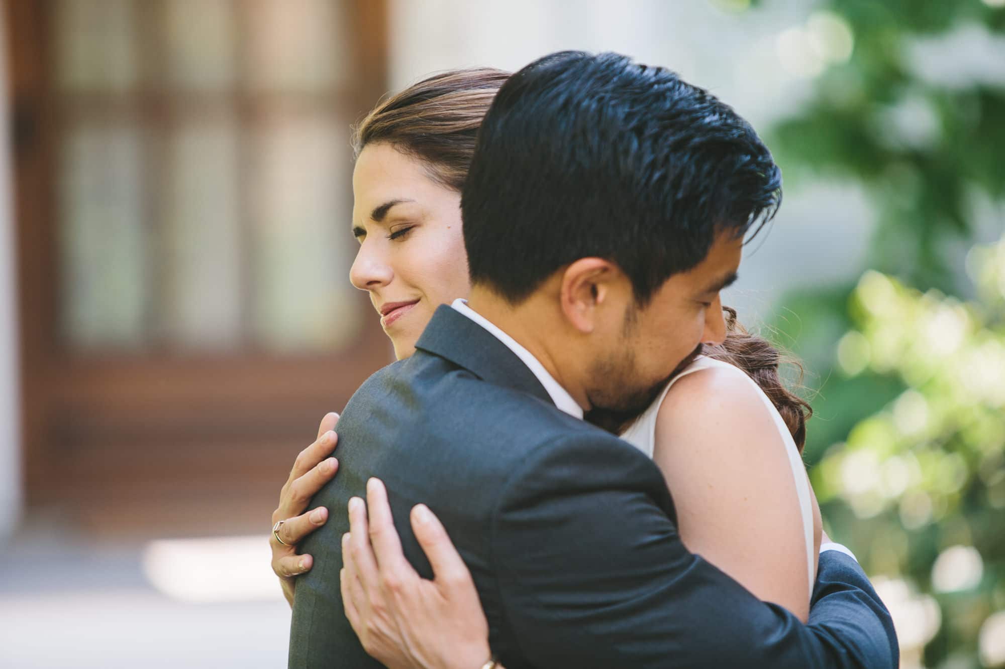 A natural portrait of a couple sharing a long hug as they see each other before their Artist for Humanity Wedding in Boston, Massachusetts