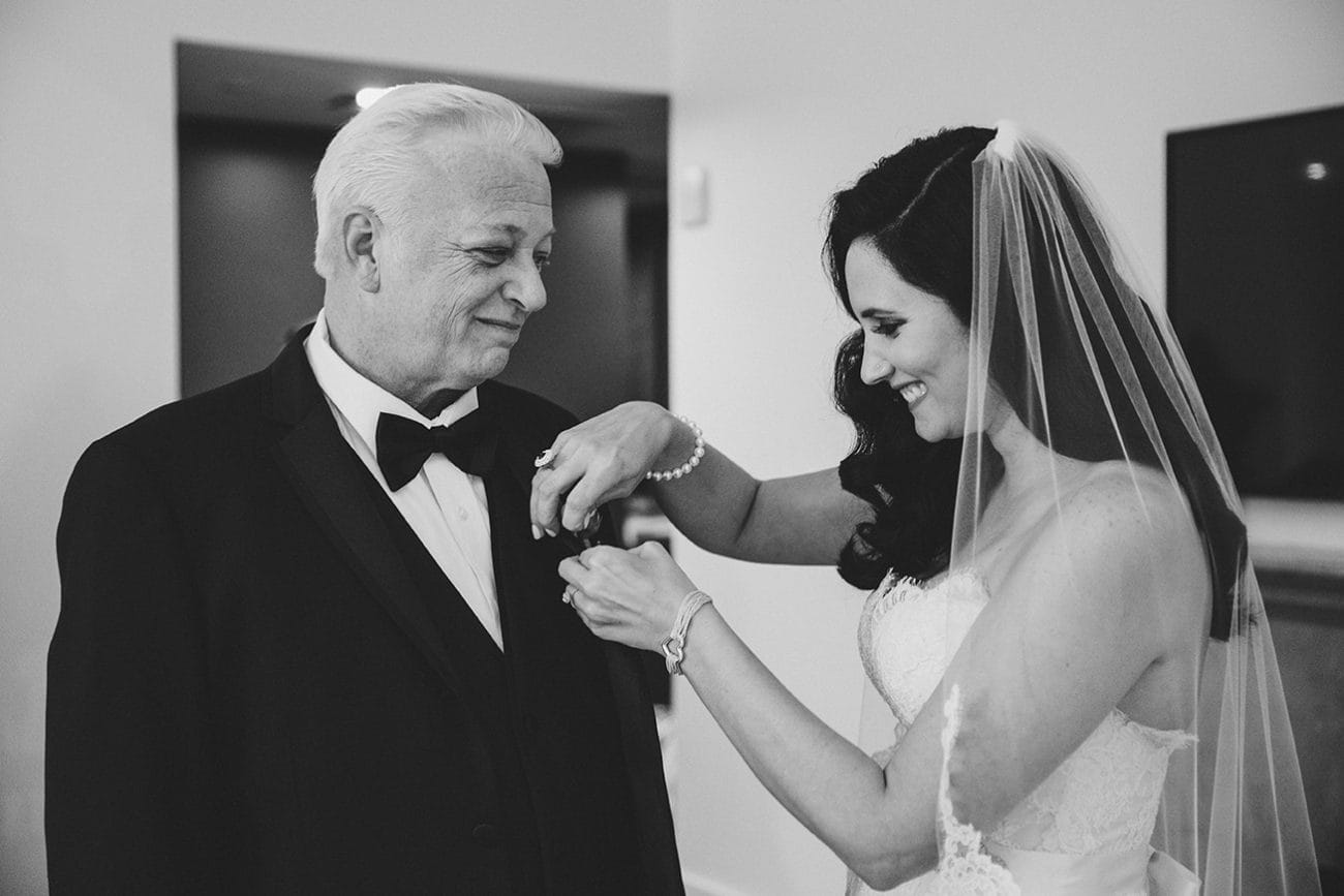 A documentary photograph of bride putting a boutonniere on her father before her old south meeting house and marliave wedding in Boston, Massachusetts