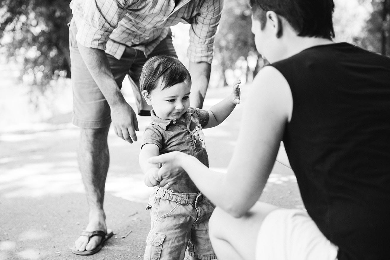 A documentary photograph of a baby walking to his momma during a Jamaica Pond family session in Boston, Massachusetts
