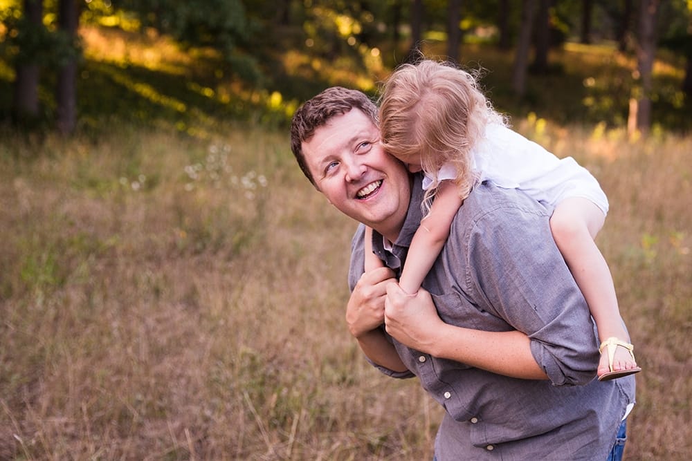 A documentary photograph of a little girl hugging her dad during their Arnold Arboretum Family Session in Boston, Massachusetts
