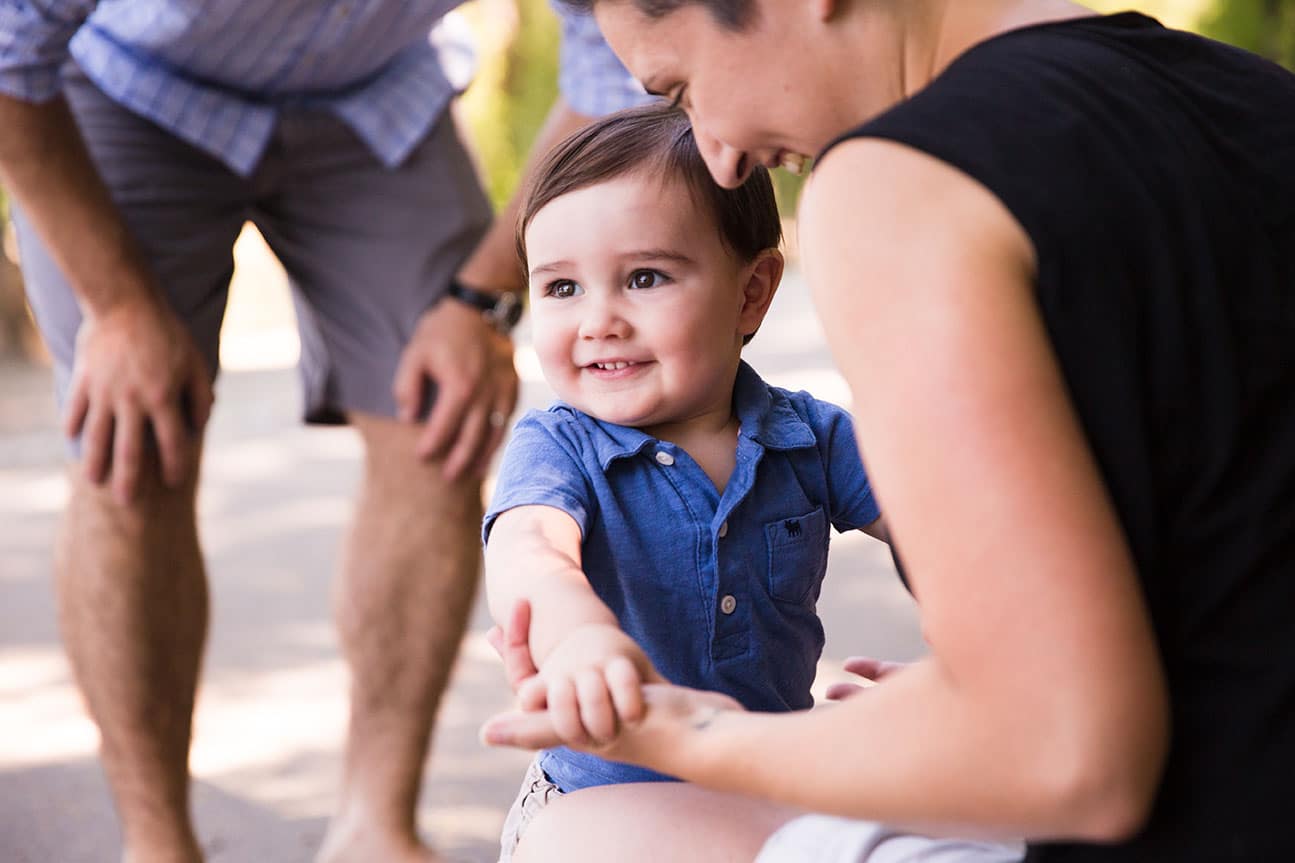 A documentary photograph of a baby walking to his momma during a Jamaica Pond family session in Boston, Massachusetts