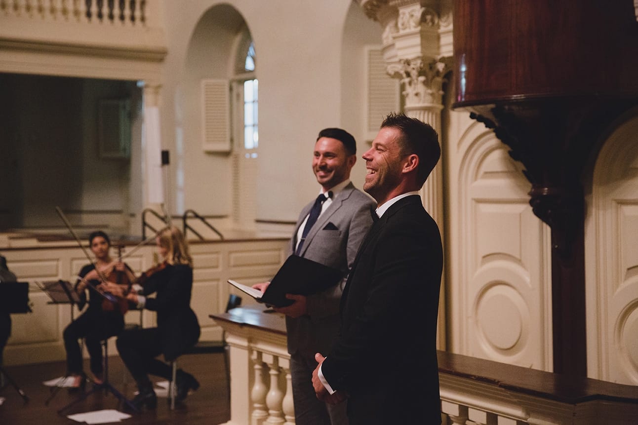 A documentary photograph of a groom smiling while he waits for his bride during their old south meeting house and marliave wedding in Boston, Massachusetts