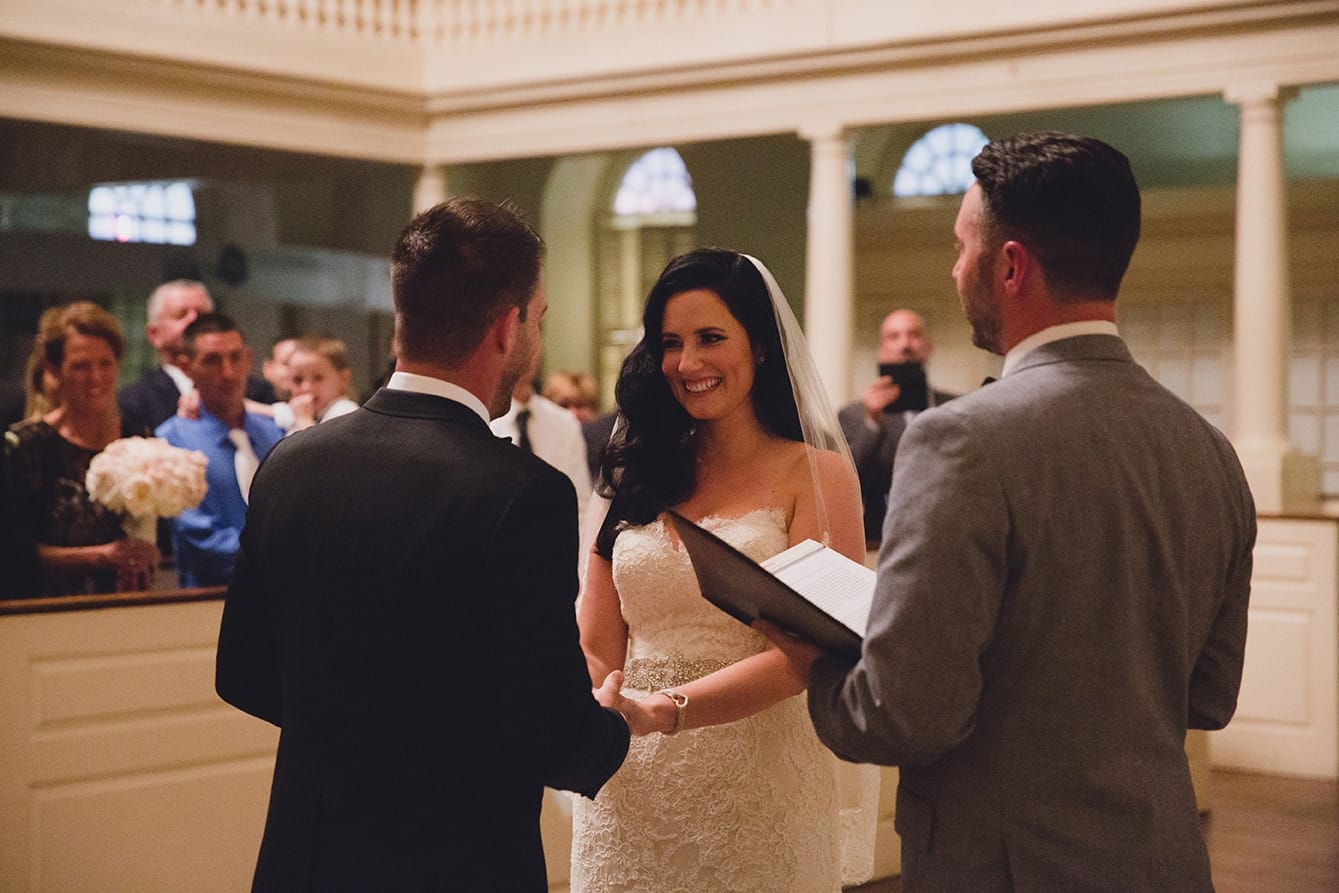 A documentary photograph of a bride and groom saying their vows during their old south meeting house and marliave wedding in Boston, Massachusetts
