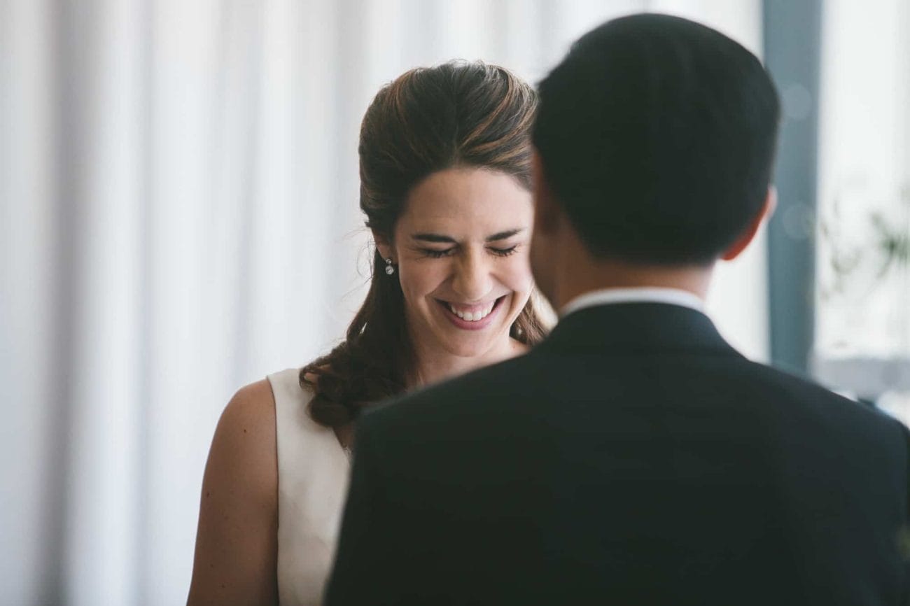 A documentary photograph of a bride smiling as she hears the vows at her Artists for Humanity Wedding in Boston, Massachusetts