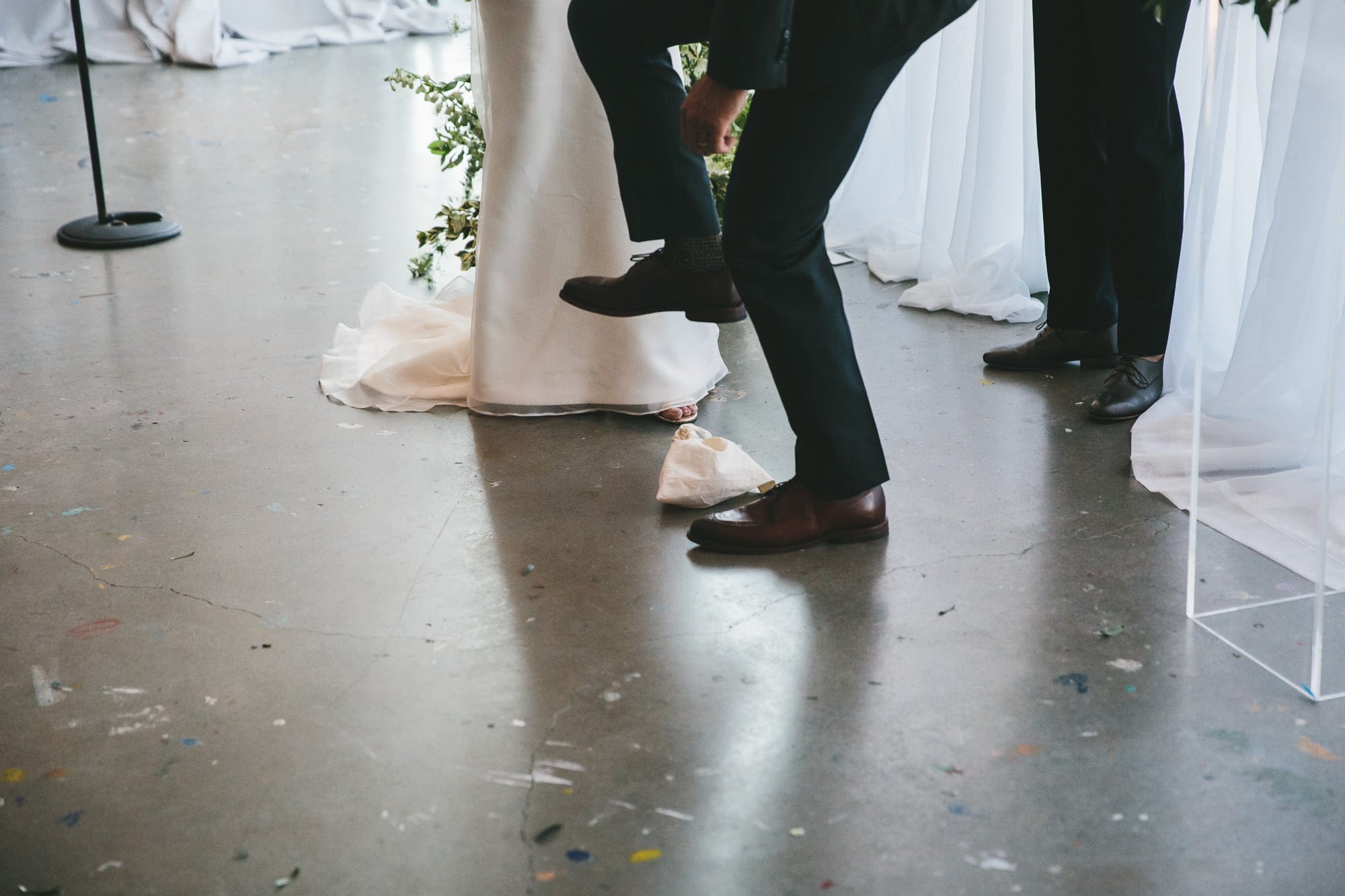 A documentary photograph of a groom smashing the glass during an Artists for Humanity Wedding in Boston