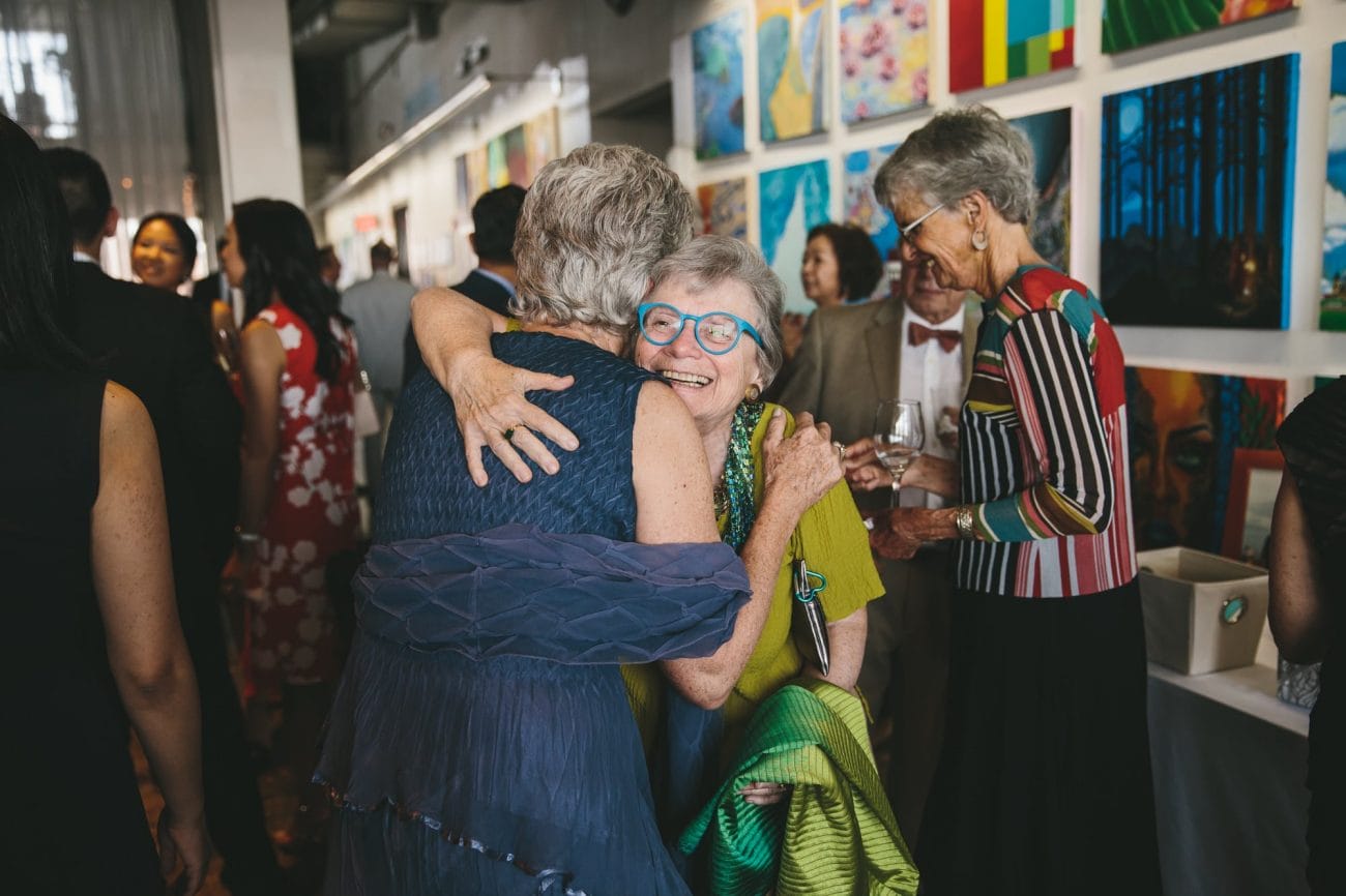 A documentary photograph of guests hugging during an Artists for Humanity wedding in Boston