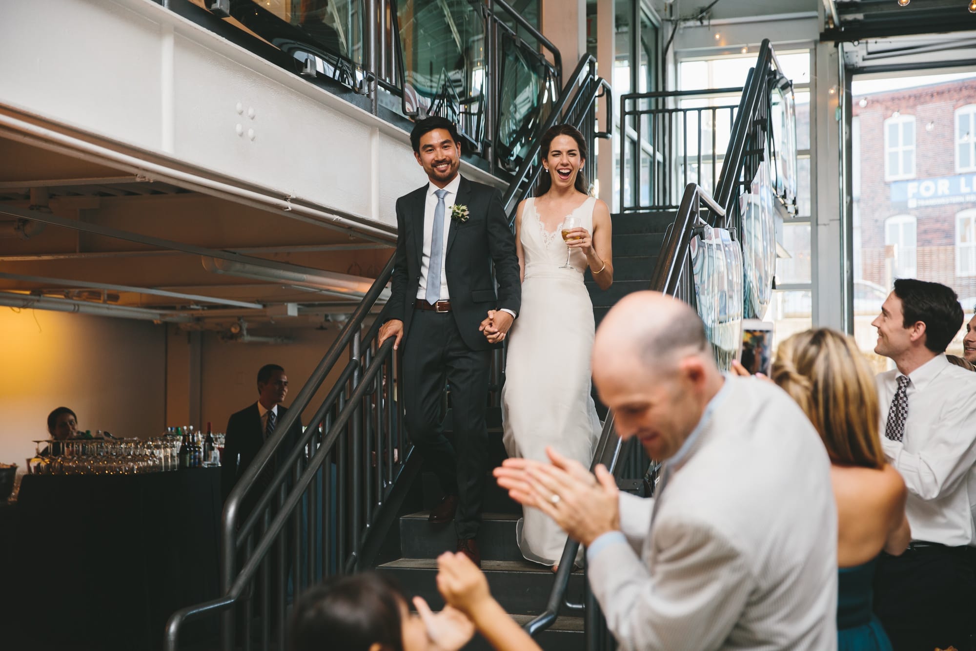 A documentary photograph of a bride and groom entering the dining room at their Artists for Humanity Wedding in Boston