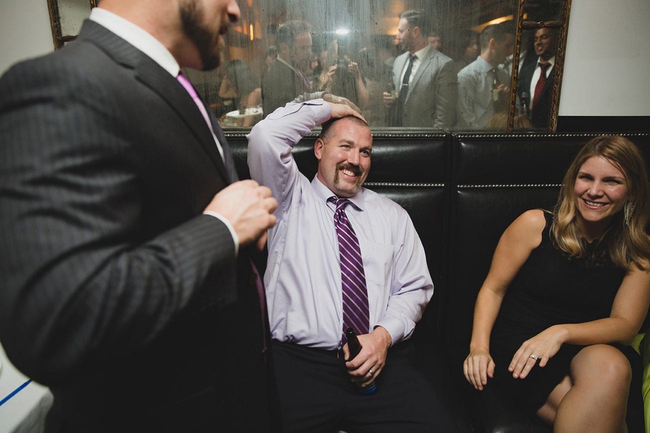 A documentary photograph of guests laughing during a marliave wedding reception in Boston, Massachusetts