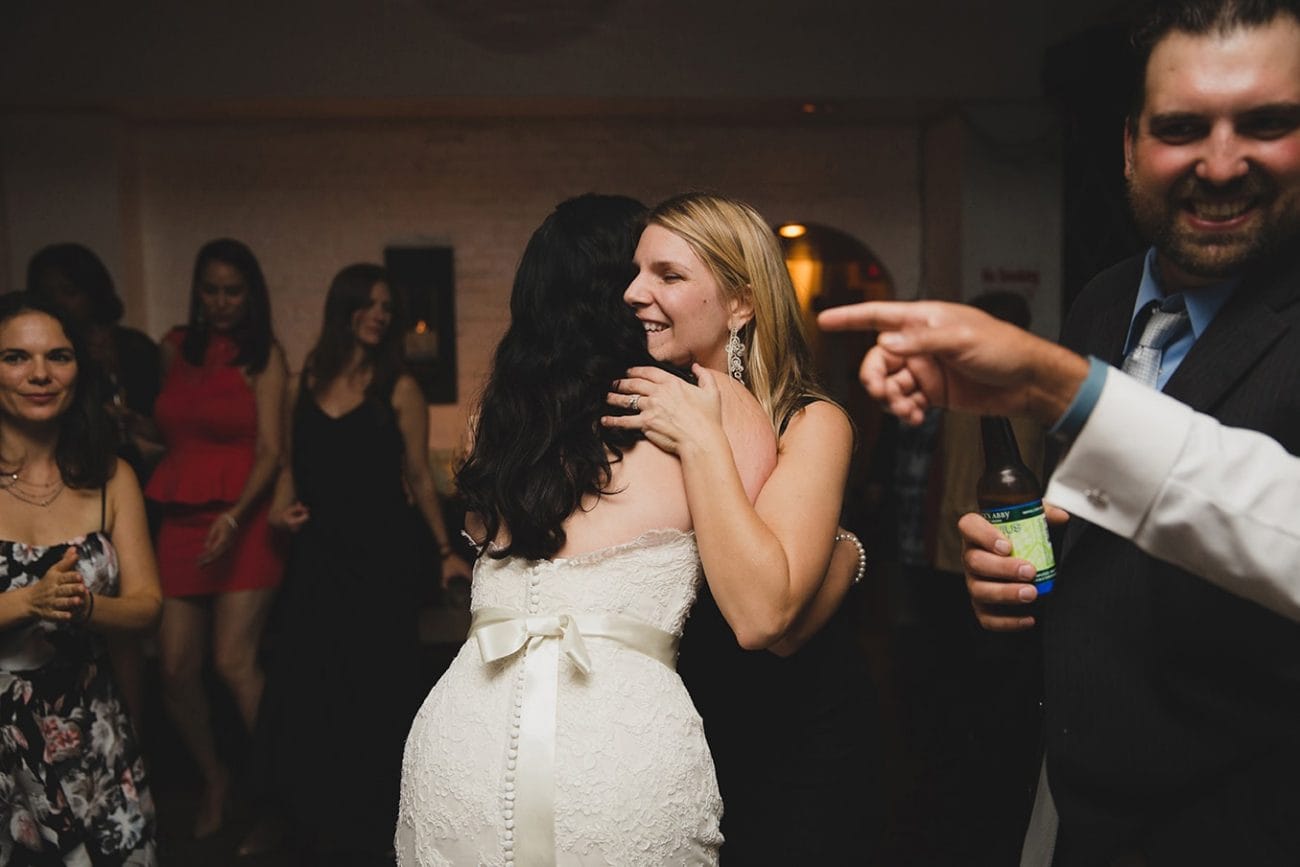 A documentary photograph of a bride hugging her friend during her old south meeting house and marliave wedding in Boston, Massachusetts
