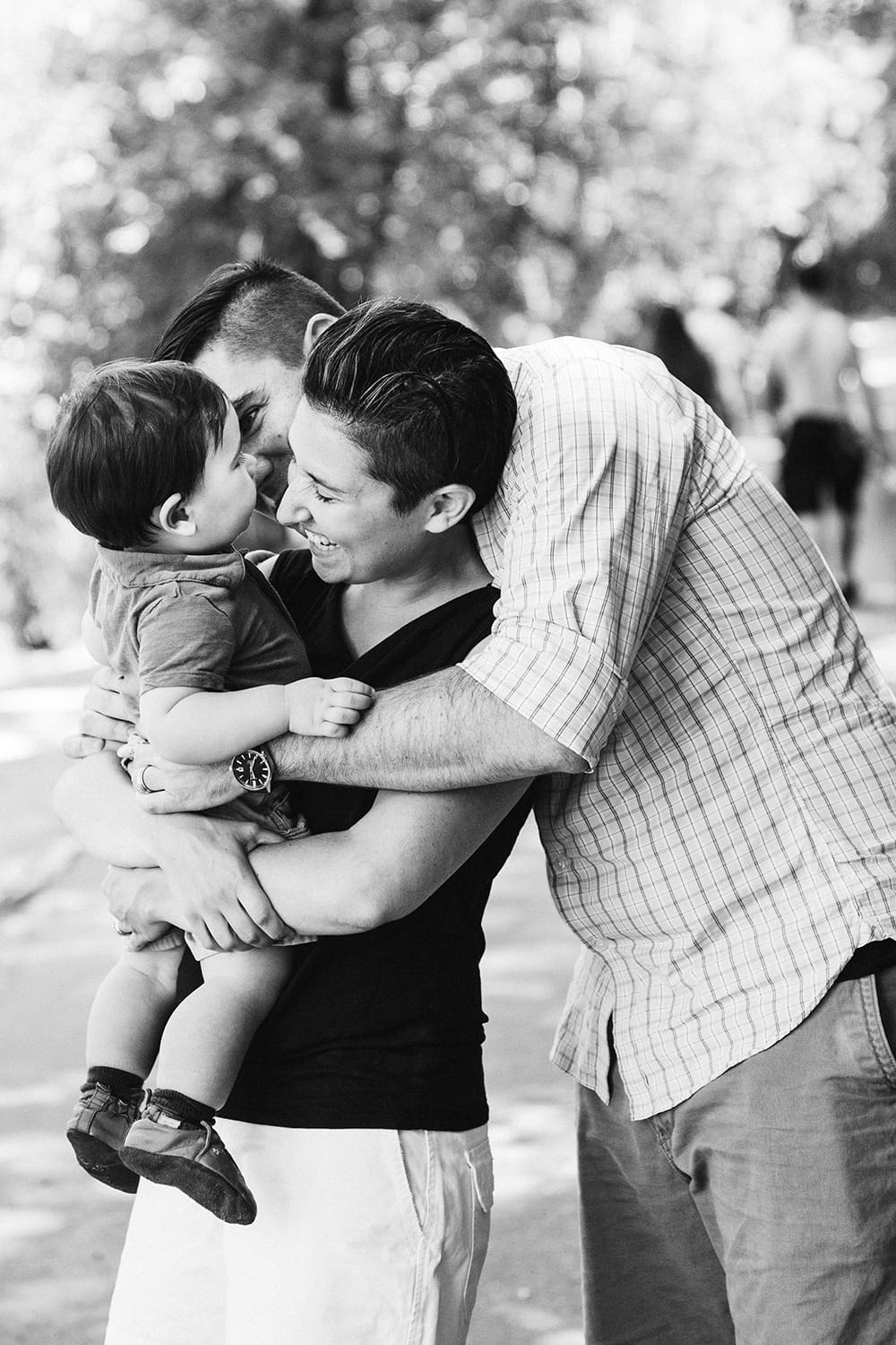 A lifestyle portrait of a family laughing and cuddling during a Jamaica Pond family session in Boston, Massachusetts