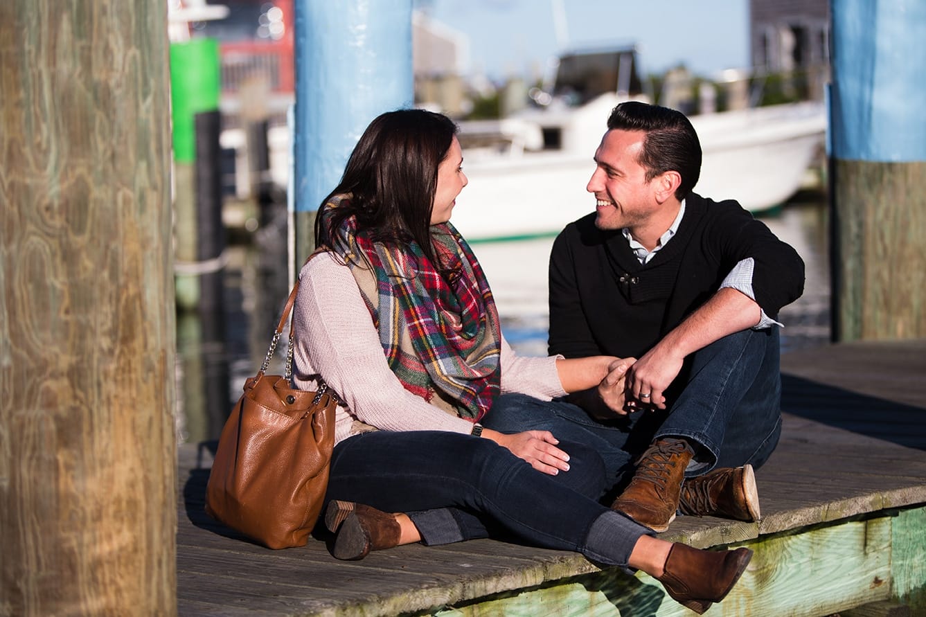 A documentary photograph of a couple talking together as they sit on the dock during their honeymoon photo session on Martha's Vineyard